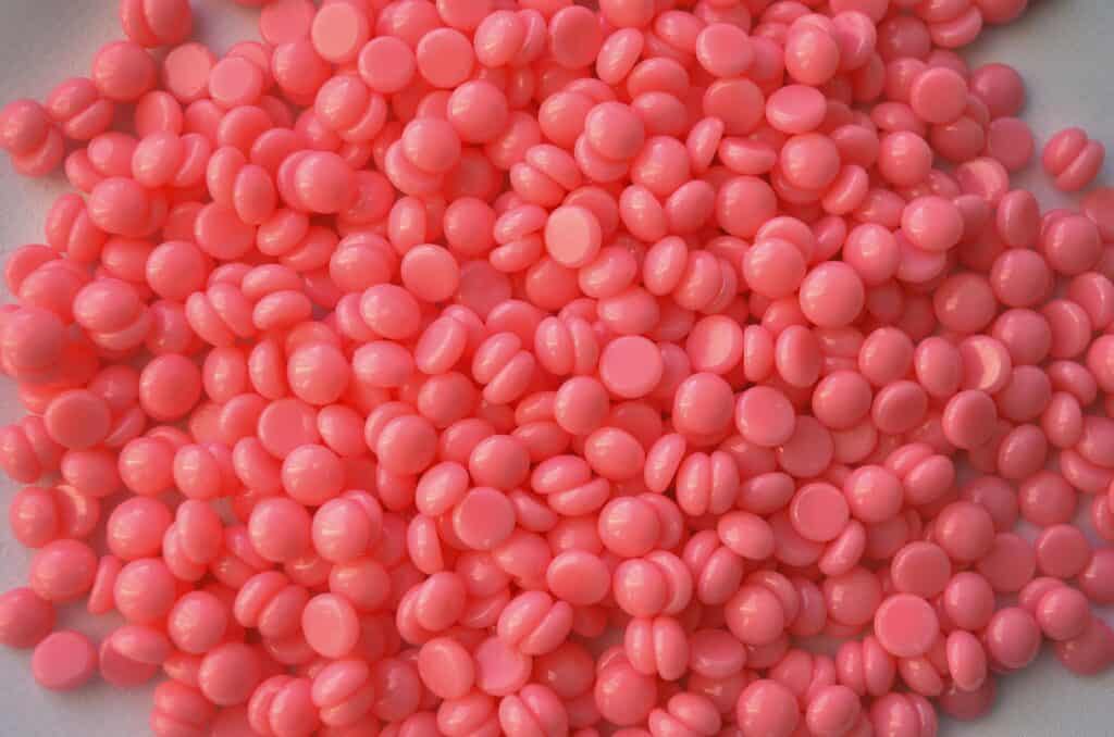 Close-up of pink wax beads used in cosmetic depilation and hair removal treatments.